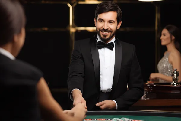 Uma mulher em um vestido verde luxuoso ao lado de uma roleta ornamentada, capturando o clima sofisticado do 63VS.